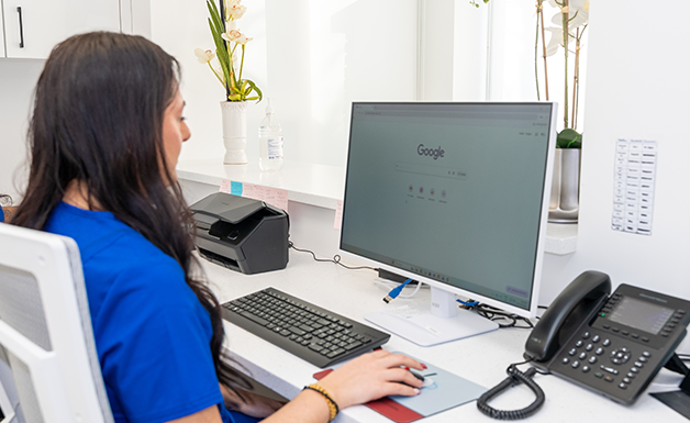 Dental receptionist working at the front desk computer.