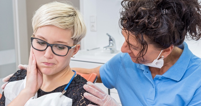 A dentist comforting her female patient with dental issues gently reassuring her 1